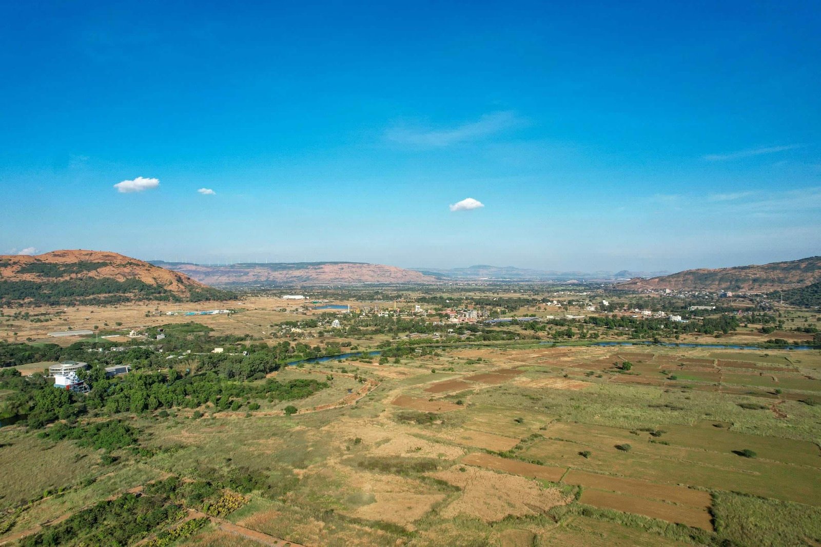 Aerial view of residential plots with open land and scenic hills